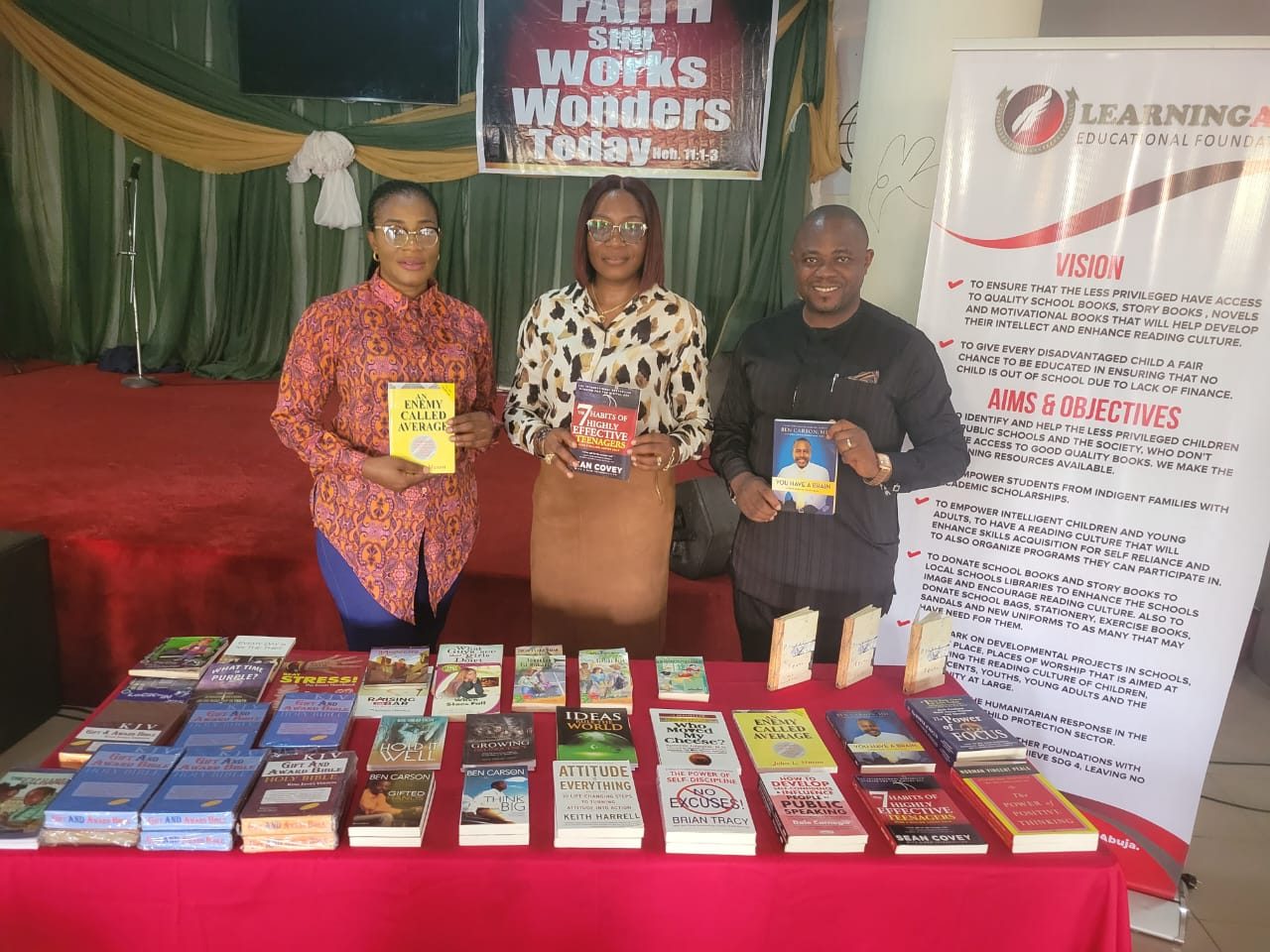 Three people holding books at a teens church donation.