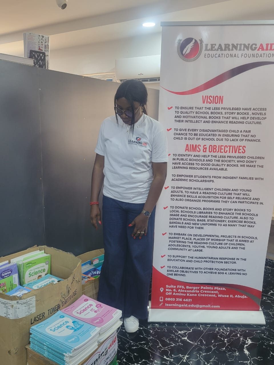 Stacks of school books beside the LEF banner, ready for donation.